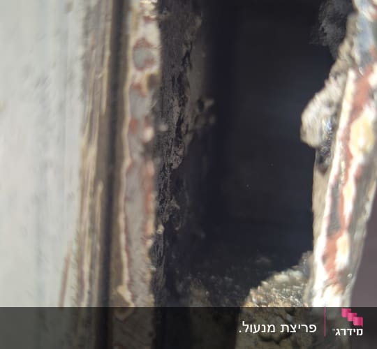 תקריב של חור שנוסר או נפרץ בדופן מתכת של כספת